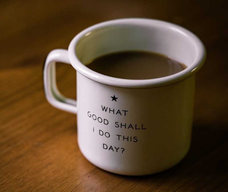 white and black ceramic cup filled with brown liquid on brown wooden sufface