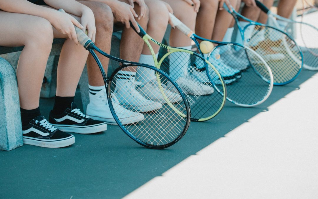 person in black and white nike sneakers holding blue and white tennis racket