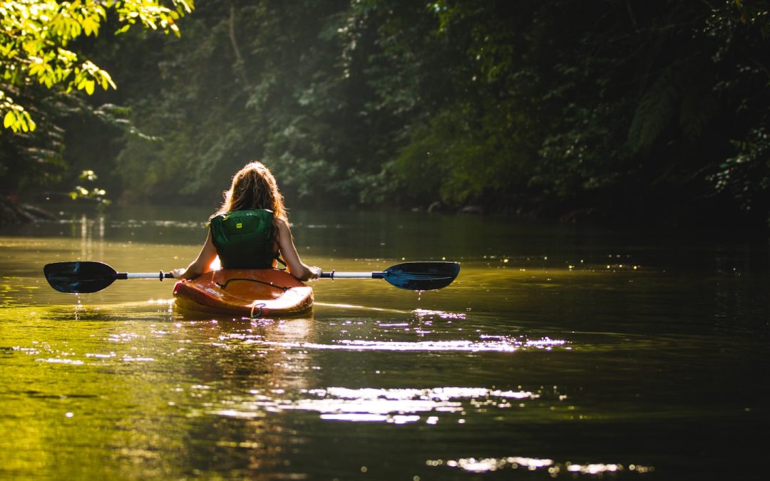 woman on kayak on body of water holding paddle