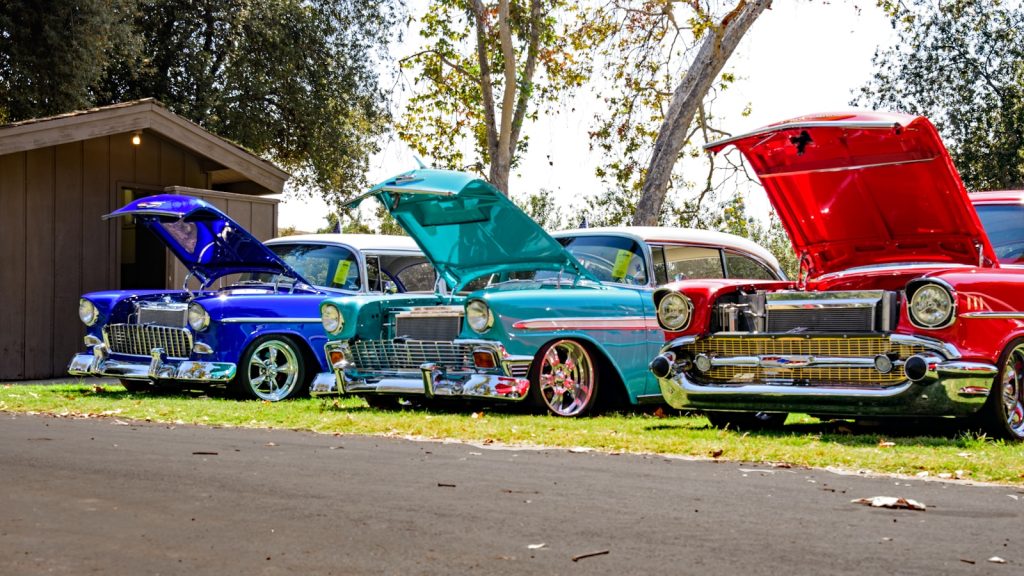 three red, blue, and teal classic cars